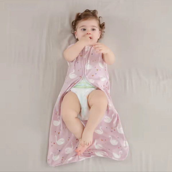 Child wrapped in a pink blanket with white patterns on a plain background