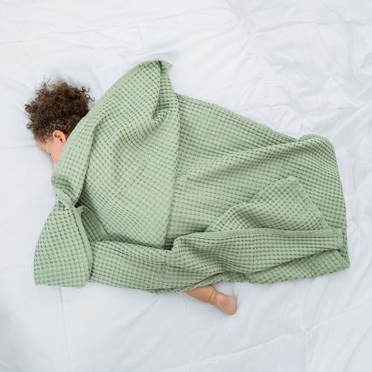 Person lying on a bed under a green checkered blanket